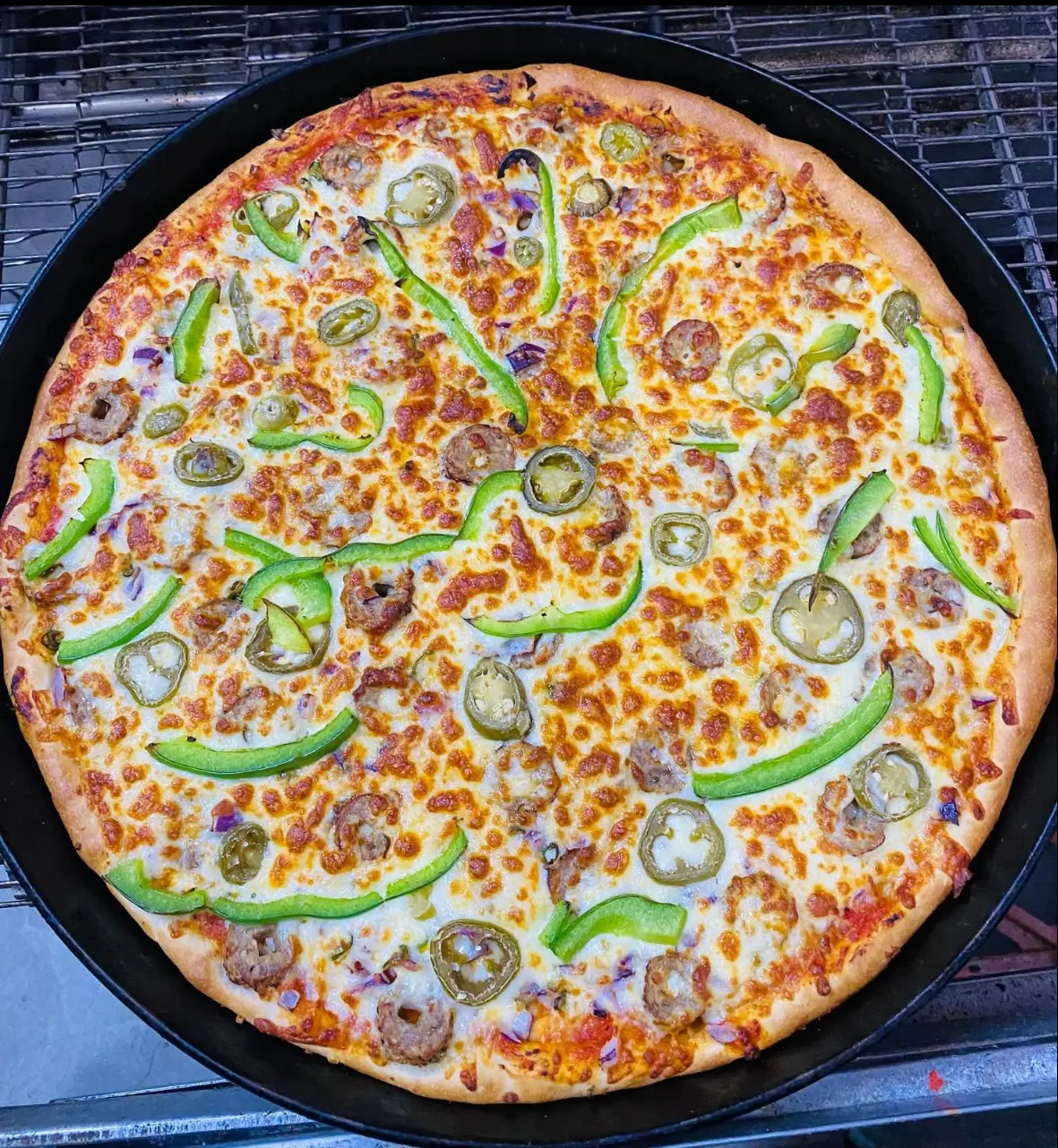 Freshly baked pizza with peppers, jalapeños and meat toppings