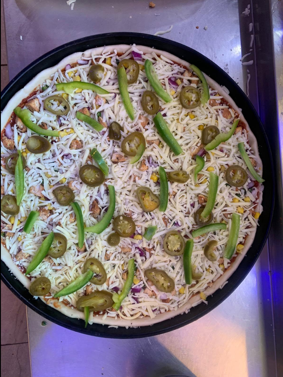 Pizza topped with chicken, peppers, jalapeños and sweetcorn