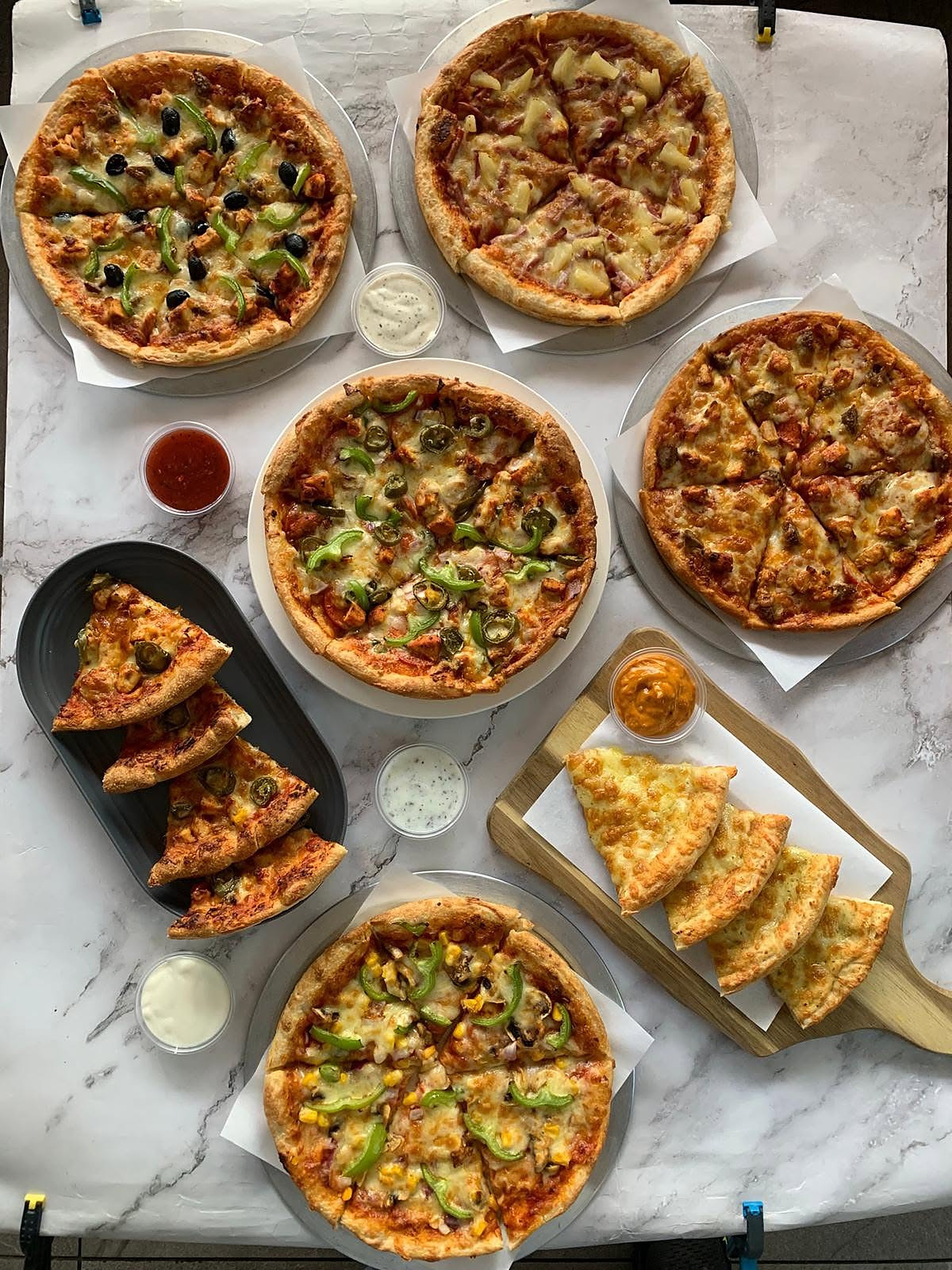 A table spread of freshly made pizzas, garlic bread and dips at Sunny's Fish Bar